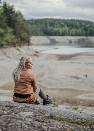 Portrait von Frau, die auf einem Felsen sitzt am Forstsee