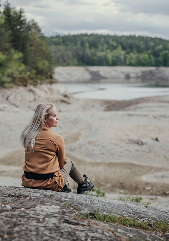 Portrait von Frau, die auf einem Felsen sitzt am Forstsee