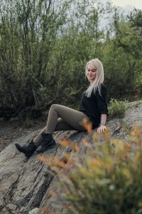 Portrait von Frau, die auf einem Felsen sitzt und lächelt am Forstsee